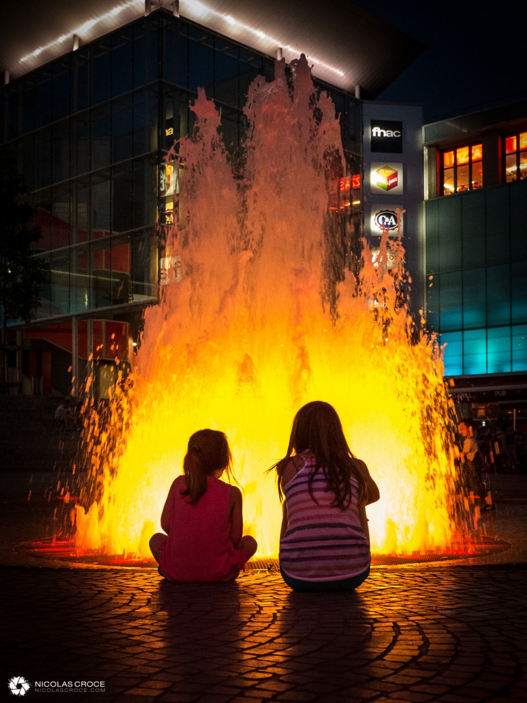 Des enfants regardent la fontaine de la place de Jaude, qui simule un volcan en éruption
