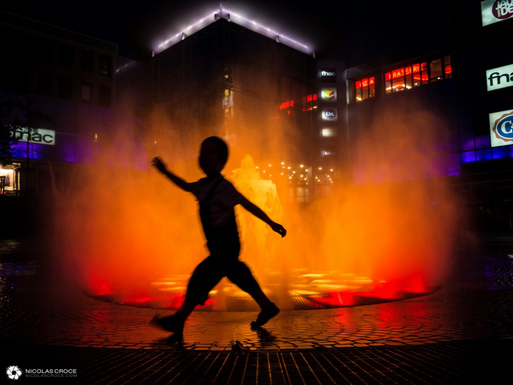 Un enfant joue devant la fontaine de la place de Jaude, qui simule un volcan en éruption